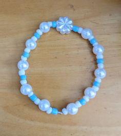 A blue and white seed bead bracelet with faux pearls and a flower centerpiece bead, fit for any occasion, fancy or not. White Beaded Pearl Bracelet With Flower Shape, White Beaded Pearl Bracelet With Flower Design, White Beaded Flower Pearl Bracelet, Blue Pearl Beaded Bracelets For Beach, Turquoise Beaded Pearl Bracelets, Adjustable Blue Pearl Beaded Bracelets, Blue Beaded Pearl Bracelet With Round Beads, Blue Pearl Beaded Bracelets For Gifts, Blue Beaded Pearl Bracelet