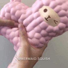 a hand holding a pink stuffed animal in the shape of a sheep