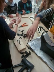 a group of people standing around a wooden table with scissors and pliers on it