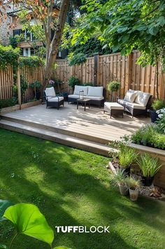 an outdoor deck with chairs and plants in the grass next to a wooden fence, surrounded by greenery