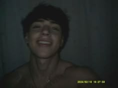 a man smiling in the dark with no shirt on