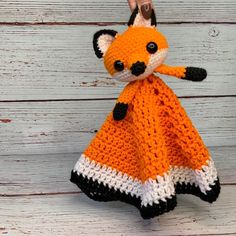 an orange and white crocheted fox stuffed animal sitting on top of a wooden floor