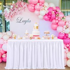 a table with cake, cupcakes and balloons on it in front of a sign that says layla