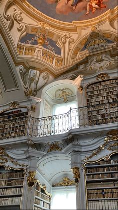 an ornate building with many bookshelves and angels painted on the ceiling above them