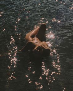 a woman floating on her back in the water with sparkles all over her body