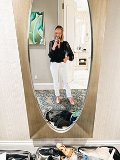 a woman taking a selfie in front of a mirror with clothes on the floor