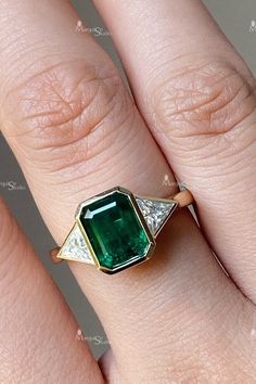 a woman's hand with an emerald and diamond ring