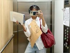 a woman is taking a selfie with her cell phone and some papers in front of her