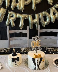 a table topped with two cakes covered in white frosting and black bow tie decorations