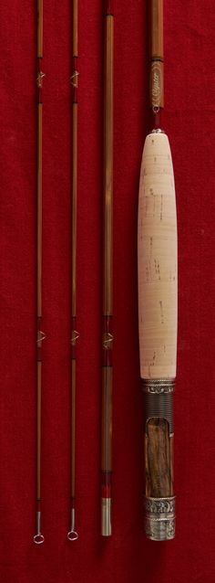 three different types of fishing rods on a red surface with two poles attached to them