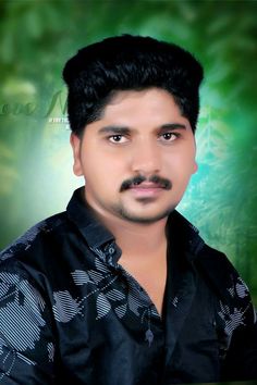 a man with black hair and a mustache in front of a green background, wearing a black shirt