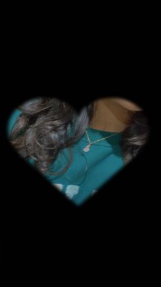 a woman laying on top of a bed next to a black heart shaped object in the dark