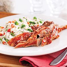 a white plate topped with meat and rice