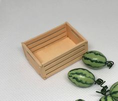 three watermelons sitting on top of each other next to a wooden box and string