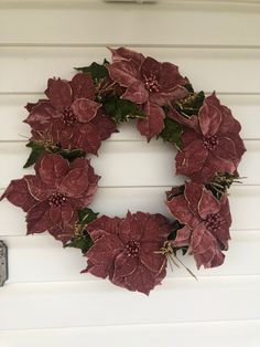 a wreath with red poinsettias hanging on a white wall