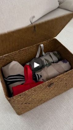 an open cardboard box filled with clothes on top of a white tablecloth covered floor