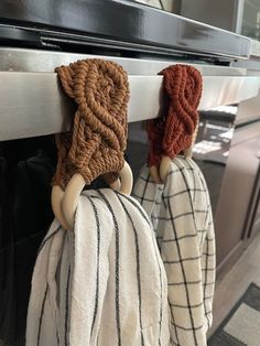 two knitted hats hanging from the handle of an oven