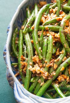 green beans with toasted nuts in a blue and white bowl on top of a table