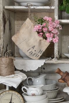 a shelf filled with dishes and flowers on top of each other, next to a clock