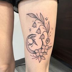 a woman's leg with a flower and crescent tattoo on the side of her thigh