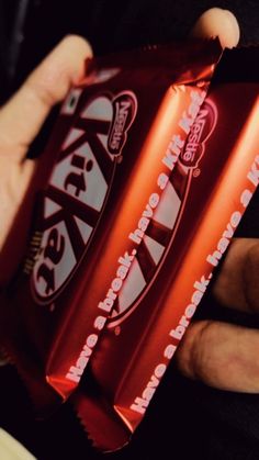 a person holding two bars of chocolate in their hands, one is red and the other is white