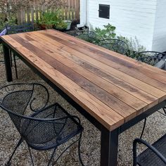 a wooden table sitting on top of a gravel covered ground next to chairs and tables