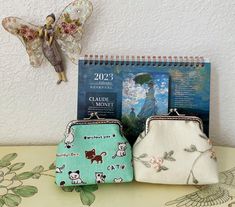 two small purses sitting on top of a table next to a calendar and angel