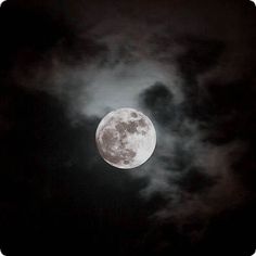 the full moon is seen through clouds in this black and white photo with dark colors