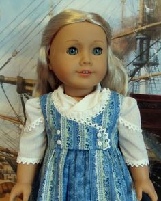 a doll with blonde hair wearing a blue dress and white collared shirt is standing in front of a pirate ship