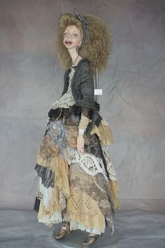 a mannequin dressed in an old fashion dress and holding a stick with her hair