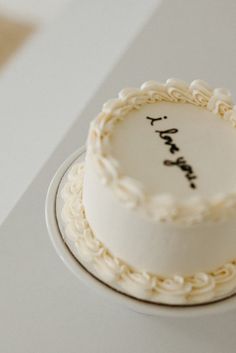 a white cake sitting on top of a table next to a knife and fork with writing on it