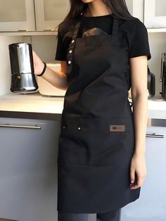 a woman in an apron is holding a coffee pot while standing next to a counter