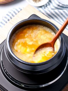 there is a pot on top of the stove with eggs in it and a wooden spoon