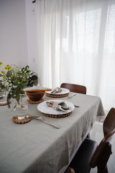 the table is set with plates, silverware and flowers in vases on it