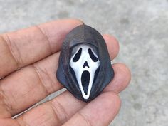 a hand holding a black and white ring with a screamy face on it's side