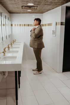 a man standing in front of a row of sinks with his hands on his chin