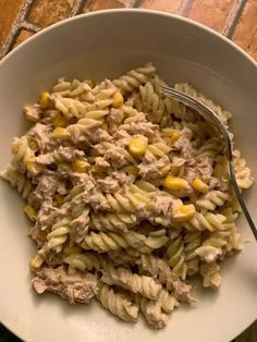 a pasta dish with tuna and corn in a white bowl on top of a table