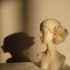 the shadow of a woman's head on a wall next to a vase with a flower in it