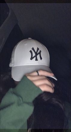 a person wearing a new york yankees hat in the back seat of a car at night