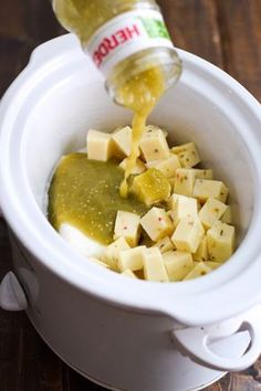 a bottle of ketchup is being poured into a bowl filled with diced potatoes