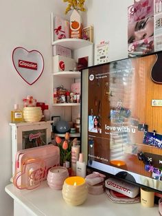 a flat screen tv sitting on top of a white table next to a pink purse