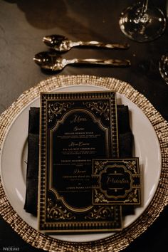 an elegant black and gold wedding set on a white plate with silverware, napkins and utensils