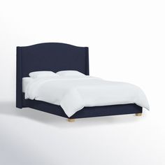 an upholstered bed with white linens and blue headboard, against a white wall