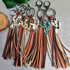 six pairs of key chains with different colors and designs on them next to a plant