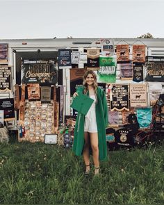 a woman standing in front of a food truck with posters on the wall behind her