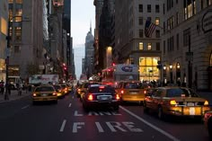 a city street filled with lots of traffic and tall buildings at night, during the day