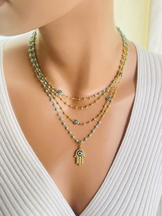 This is a gorgeous 14 karat gold filled multi strand necklace. This necklace features aqua chalcedony and gold pyrite stones.  Hamsa pendant that measures 22X 18 MM. Faceted stones  measure 2.5-3MM. Beautiful aqua Marano glass Evil eye connectors are scattered on this necklace. Toggle in back connects all four strands. This necklace is much more stunning in person. Necklace strands are 15 to 18 inch. Necklace Women Gold, Hamsa Necklace Gold, Necklace Evil Eye, Necklaces Women, Gold Hamsa, Hamsa Pendant, Hamsa Necklace, Aqua Chalcedony, Necklace Women