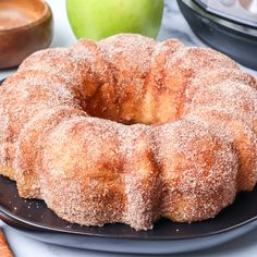 a donut sitting on top of a black plate next to an apple