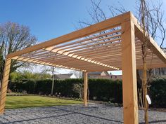 a wooden pergola sitting on top of a gravel field