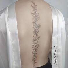 the back of a woman's neck with flowers and leaves on her left side